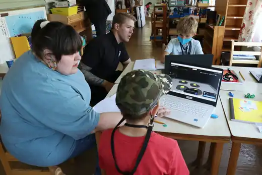 Campers and mentors gather at a laptop with a 3D model